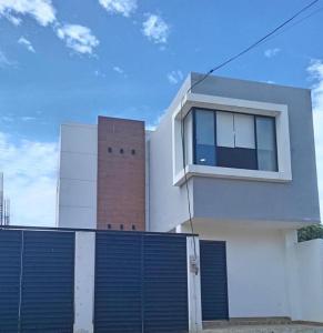 a white house with a blue gate and a brick building at FinlandHouse in Puerto López