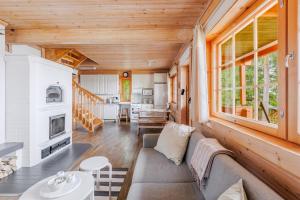 a living room with a couch and a kitchen at Tyyni Resort - Hirsihuvila Aalto in Liperi