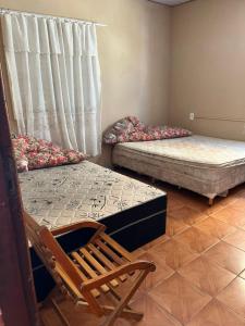 a room with two beds and a chair and a window at CasaZita in Passo De Torres +19 photos