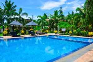 a large blue swimming pool with chairs and trees at Hotel Green Garden PVT LTD in Trincomalee