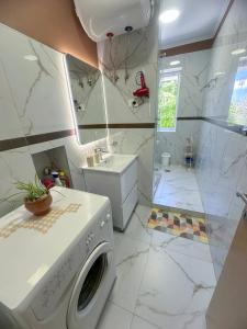 a white bathroom with a washing machine in it at Parkview Home in Korçë +16 photos