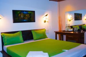 a bedroom with a bed with green sheets and a desk at Hotel Green Garden PVT LTD in Trincomalee +30 photos