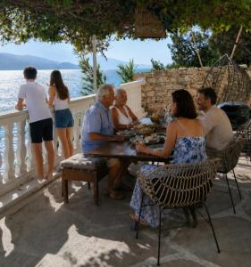 a group of people sitting around a table on a patio at Villa ZeN- with Private garden and beach in Samos