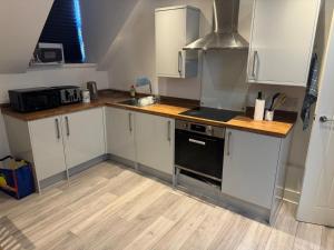 a kitchen with white cabinets and a black oven at Epsom High Street Apartment 9 in Epsom