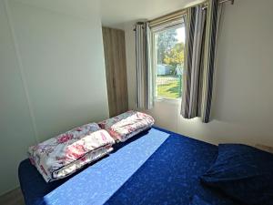 a bed with pillows on it in a room with a window at De Pujol Greenchalets Argeles sur Mer in Argelès-sur-Mer
