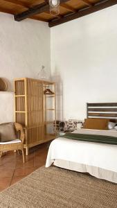 ein Schlafzimmer mit einem großen Bett und einem Stuhl in der Unterkunft Is Scabas Guestrooms in Solarussa