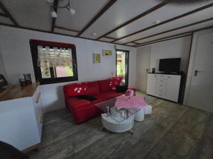 a living room with a red couch and a table at Mobilheim Chalet Chicco in Steinach