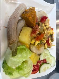 a plate of food with a sausage and vegetables at Riddim Vybz guesthouse in Kingston