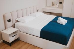 a white bed with a blue blanket and a night stand at Shehu Skenderbeg Stay in Tirana