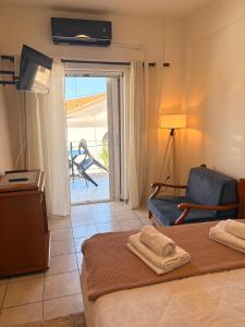 a hotel room with a bed and a chair and a patio at Port Breeze Apartments in Karlovasi