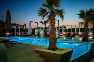 a swimming pool with palm trees next to a building at Apartmani Novia in Bibinje