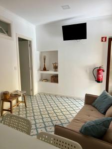 a living room with a couch and a tv on the wall at Elvas Centro Histórico Largo do Refúgio in Elvas