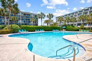 a swimming pool with chairs and a building at Oceanfront Luxury 2BR Litchfield Beach Escape in Pawleys Island