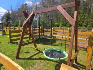 two swings in a playground with a fire pit at Domek na Czerwonej Górce in Uście Gorlickie