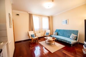a living room with a blue couch and two chairs at Mooi Panzió in Nagyatád