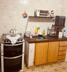 a kitchen with a stove and a sink and a microwave at Casa na Ponta da Praia - Quintais privativos, churrasqueira e Wi-fi - Até 6 hospedes in Santos
