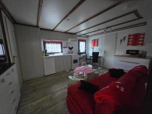 a living room with a red couch and a kitchen at Mobilheim Chalet Chicco in Steinach +4 photos