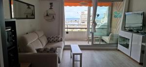 a living room with a couch and a television at Vertige Bleu, Vue mer, Port, Plage, WI-FI, Clim, Centre ville, Commerces, Calme in La Grande Motte