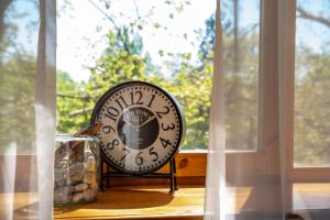 a clock sitting on a table in front of a window at Mooi Panzió in Nagyatád
