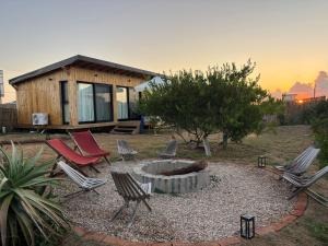 a group of chairs and a fire pit in front of a cabin at Casa Franca in José Ignacio