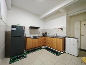 a kitchen with wooden cabinets and a black refrigerator at DH Villa in Batu Caves