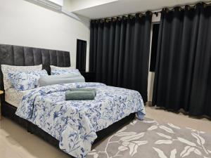 a bedroom with a large bed with blue and white sheets at DH Villa in Batu Caves