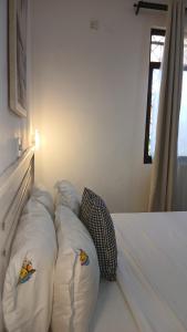 a white bed with pillows on it in a room at Imani staycations Diani 2 in Diani Beach