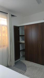 a bedroom with a bed and wooden cabinets and a window at Imani staycations Diani 2 in Diani Beach