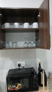 a black microwave sitting on a counter in a kitchen at Imani staycations Diani 2 in Diani Beach