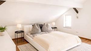 a white bedroom with a white bed and two tables at Haus OS in Bischofshofen