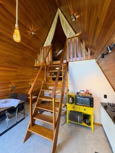 a wooden staircase in a room with a table and a kitchen at Sítio das Amoreiras- Cabana in Tabapira