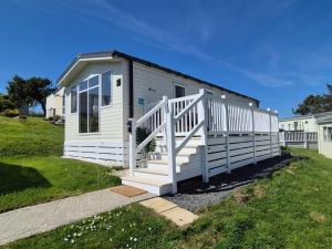 a small white house with a white railing at Joesphine Newquay Bay 37 in Newquay Bay Resort