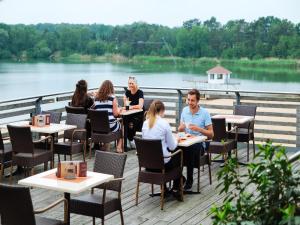 a group of people sitting at tables on a deck at Bernsteinsee Home and Ferien Small Forest Chalet in Sassenburg +17 photos