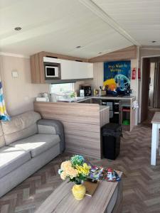 a living room with a couch and a kitchen at Surf Shack Caravan - Lyons Winkups in Kinmel Bay