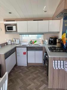 a kitchen with white cabinets and a counter top at Surf Shack Caravan - Lyons Winkups in Kinmel Bay +3 photos