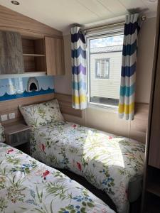 a small room with two beds and a window at Surf Shack Caravan - Lyons Winkups in Kinmel Bay