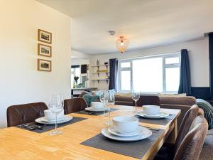 a dining room with a wooden table with glasses on it at Ocean View, 3 bed 2 bath, Dog Friendly, Private parking, Beach 9 min walk, sleeps 6 in Ilfracombe