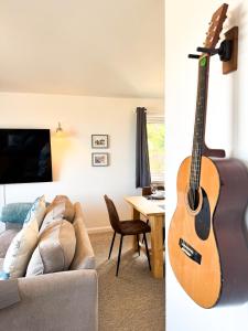 a living room with a guitar and a living room with a couch at Ocean View, 3 bed 2 bath, Dog Friendly, Private parking, Beach 9 min walk, sleeps 6 in Ilfracombe