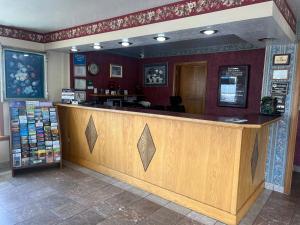 a restaurant with a large wooden bar in a room at Red Carpet Inn Medford in Medford