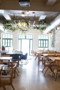 a dining room with tables and chairs and windows at ASO Hotel - Historic Raisin Warehouse 1928 in Kalamata
