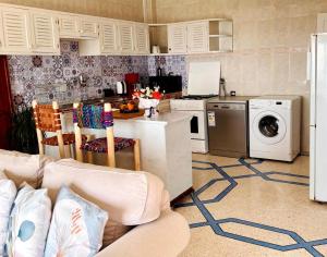 a kitchen with a couch and a washer and dryer at HeenaluSurfCamp - ocean view appartement - 4P - Tamraght in Tamraght Ouzdar +23 photos