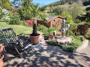 a patio with a bench and a palm tree at Ferienwohnung Siegel in Heimweiler