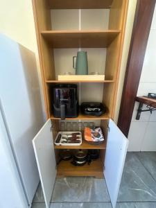 a cupboard with a coffee maker in it at Chalé do coiote! in São Roque de Minas
