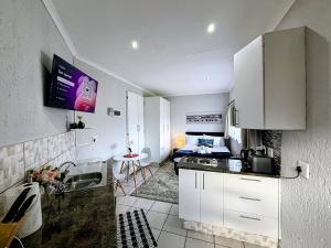 a small kitchen with white cabinets and a sink at Signature Suite in Kempton Park