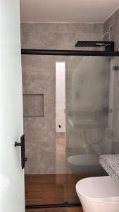 a glass shower door in a bathroom with a toilet at Quarto Personalizado Individual aconchegante novo no coração da cidade -Ufla- restaurantes e padaria in Lavras