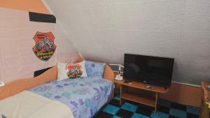 a small bedroom with a bed and a flat screen tv at William's Vendégház in Várpalota