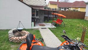 an orange motorcycle parked in a yard with a grill at William's Vendégház in Várpalota