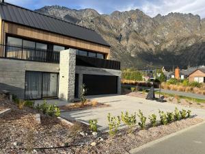 a house with a large garage in front of a mountain at Jacks Point Getaway in Queenstown Airport