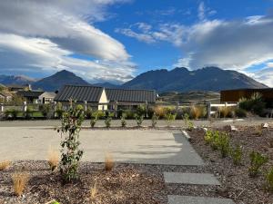 a parking lot with a building and mountains in the background at Jacks Point Getaway in Queenstown Airport +2 photos