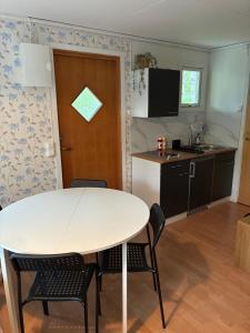 a kitchen and dining room with a white table and chairs at Nyrenoverad stuga mellan två sjöar in Järlåsa